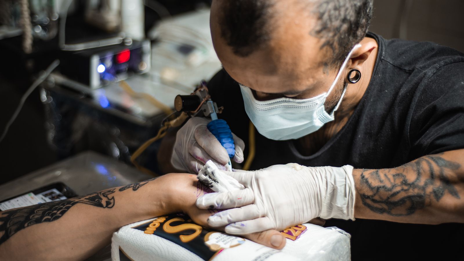 Tatuatore con guanti bianchi durante una seduta