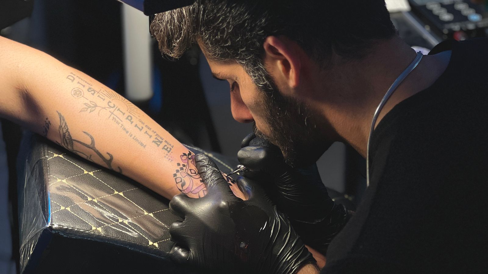 Tatuatore al lavoro sul braccio di un cliente